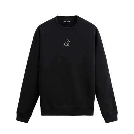 Siyah sweatshirt üzerinde beyaz çizgiyle minimal tavşan tasarımı.
