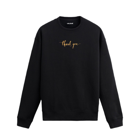 Siyah sweatshirt üzerinde göğüs kısmında altın tonlarında yazılmış “thank you” ifadesi bulunan minimal tasarım.