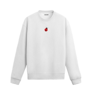 Beyaz sweatshirt üzerinde göğüs kısmında kırmızı küçük uğur böceği baskısı bulunan minimal tasarım.