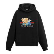 Üzerinde “More Chill” yazısı bulunan, rahat pozisyonda uzanmış ayıcık baskılı hoodie tasarımı.